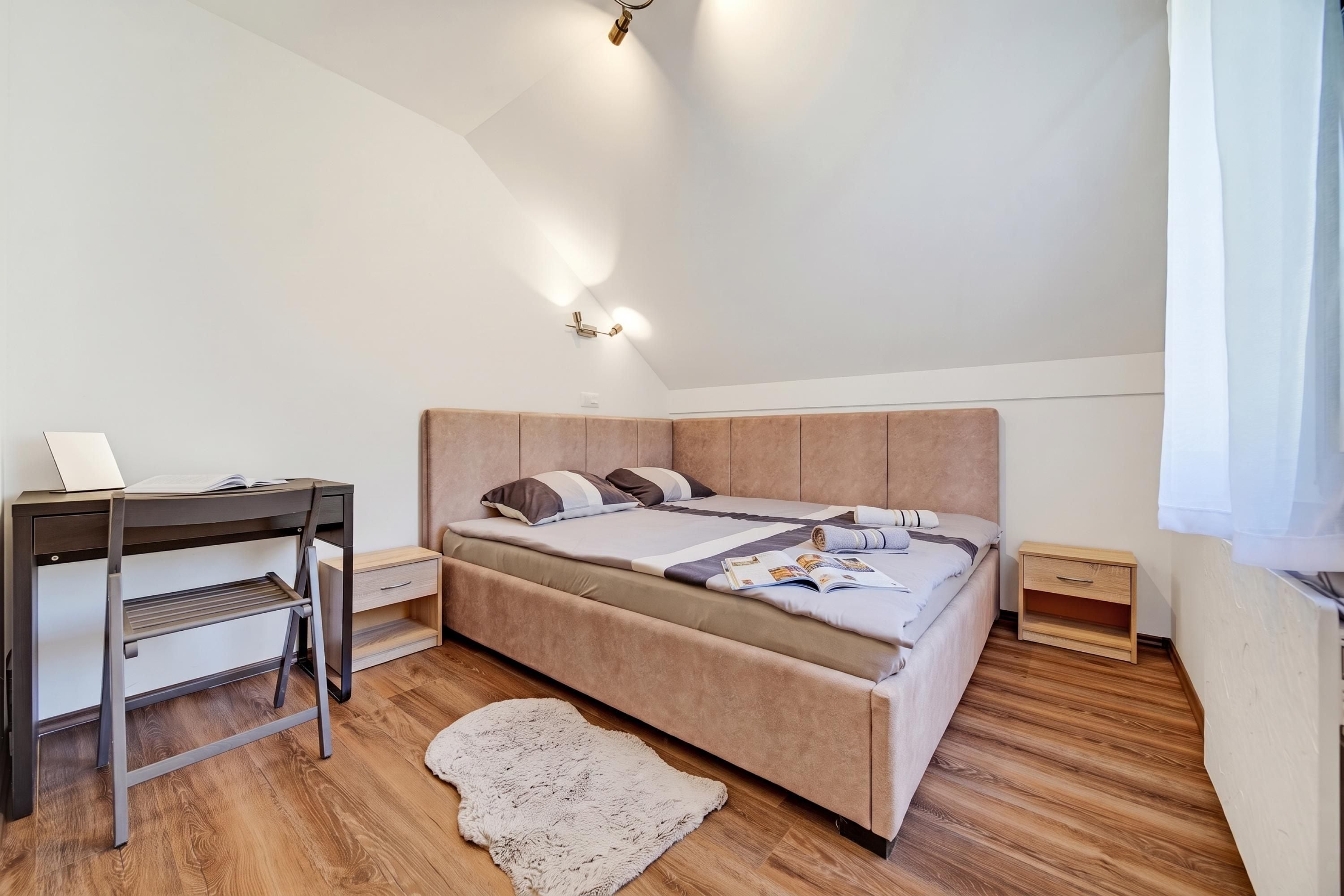 Un dormitorio con una cama, un escritorio y una mesita de noche.