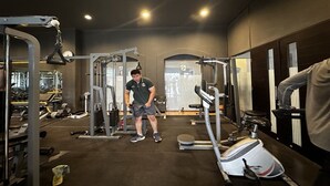 Un gimnasio con diversos equipos de ejercicio, incluyendo una jaula para sentadillas y una prensa de banca.