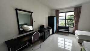 Habitación de hotel con cama, escritorio con silla, armario, espejo y ventana con cortinas.