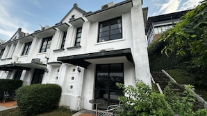 A white building with a flat roof, large windows, and a small outdoor seating area with metal chairs. - Casa D'Ladera Bandung Standard Double (Bandung)