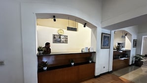 A reception area with a wooden reception desk, a clock, and framed pictures on the wall. - Casa D'Ladera Bandung Standard Double (Bandung)