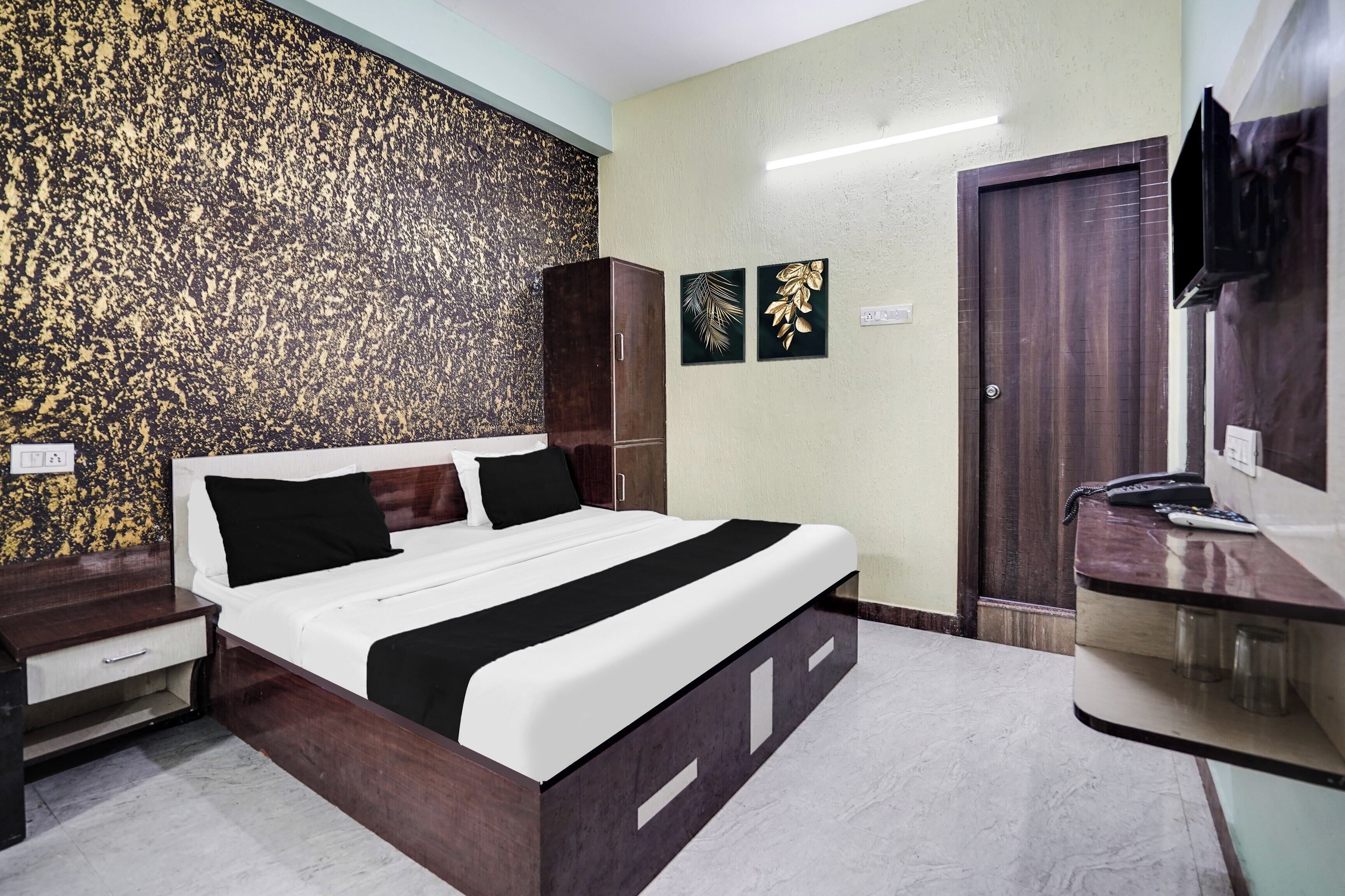 A hotel room with a bed, a wardrobe, a desk with a mirror, and a television.