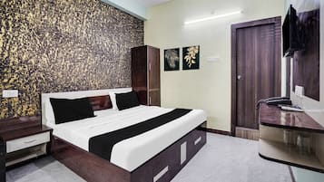 A hotel room with a bed, a wardrobe, a desk with a mirror, and a television.