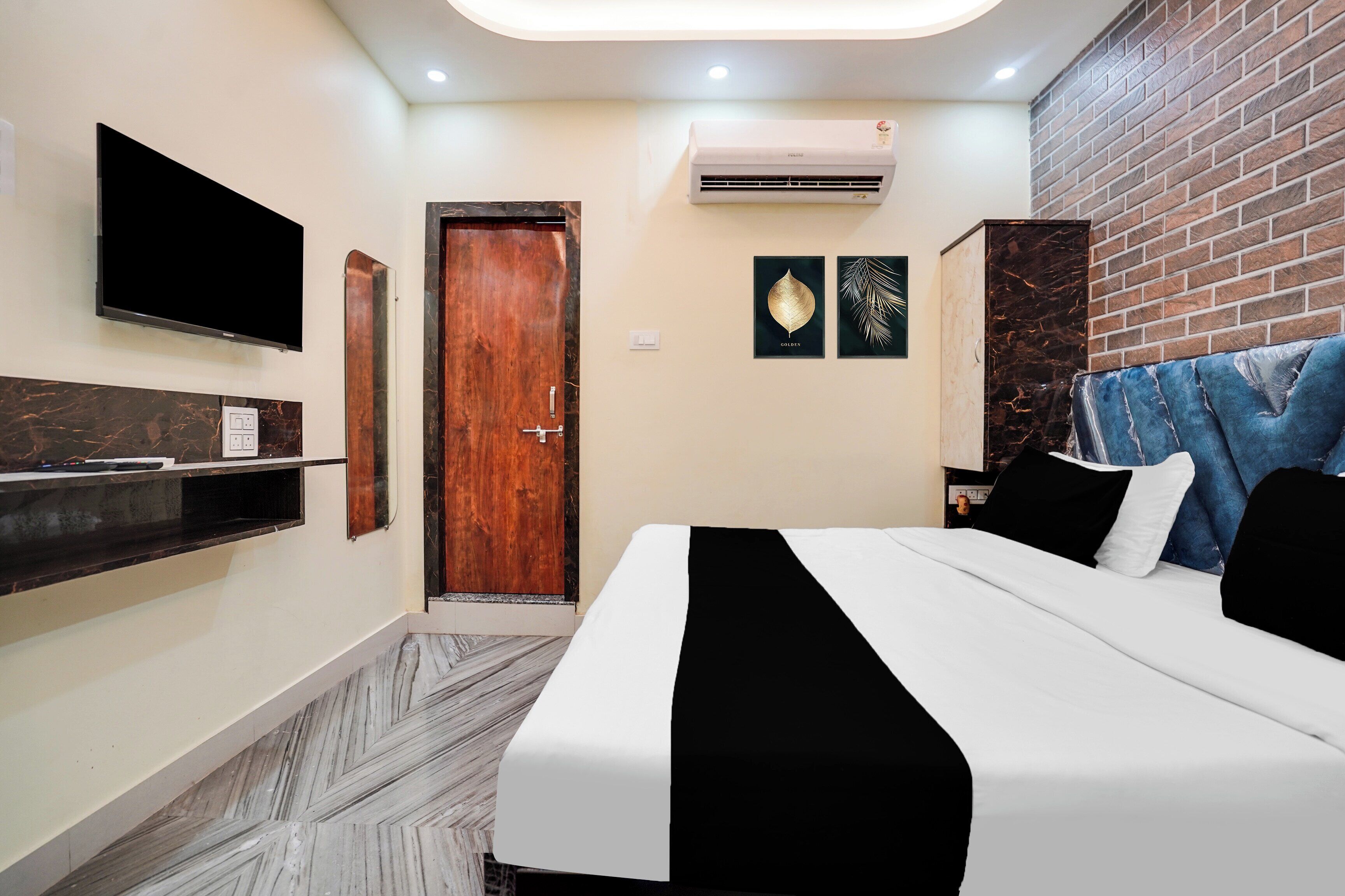 Une chambre d’hôtel équipée d’un lit, d’un téléviseur fixé au mur, d’une porte en bois et d’un appareil de climatisation.
