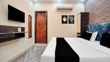 Une chambre d’hôtel équipée d’un lit, d’un téléviseur fixé au mur, d’une porte en bois et d’un appareil de climatisation.