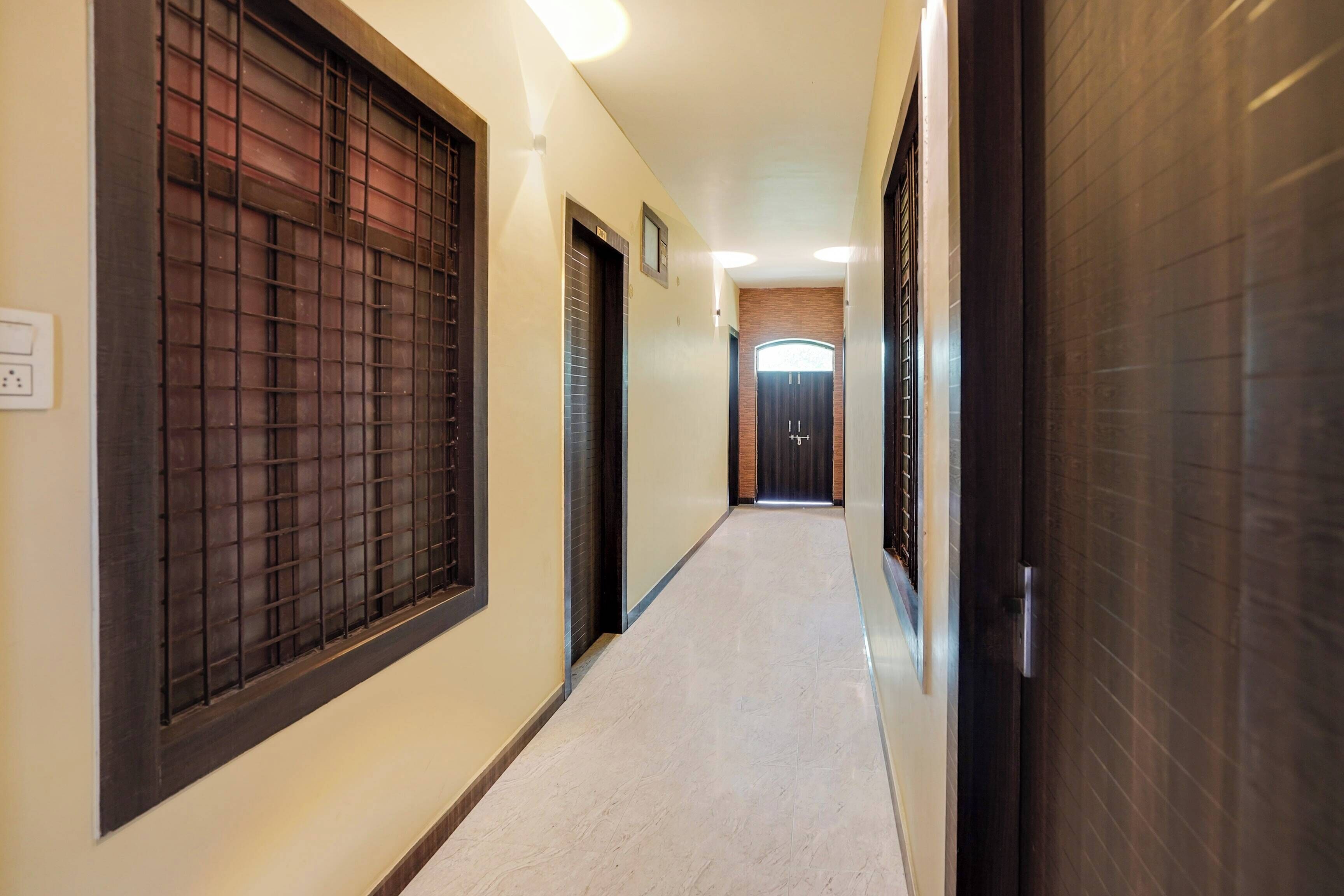 A corridor with doors on both sides, a tiled floor, and a light fixture on the ceiling.