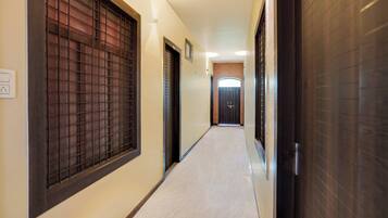 A corridor with doors on both sides, a tiled floor, and a light fixture on the ceiling.