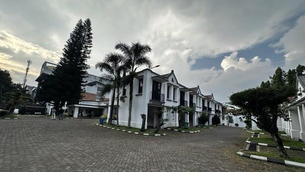 Un edificio blanco con fachada simétrica, rodeado de un patio empedrado con palmeras.