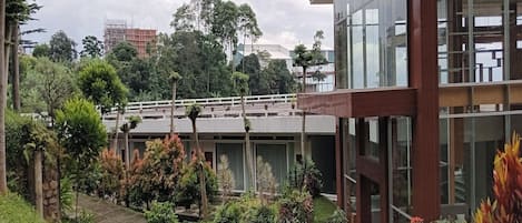 Un edificio moderno con fachada de vidrio, una galería techada y abundante vegetación.
