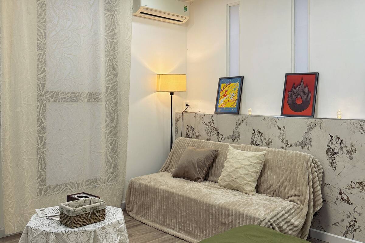 Un dormitorio con cama, una mesita de noche con una cesta, una lámpara y dos cuadros en la pared.