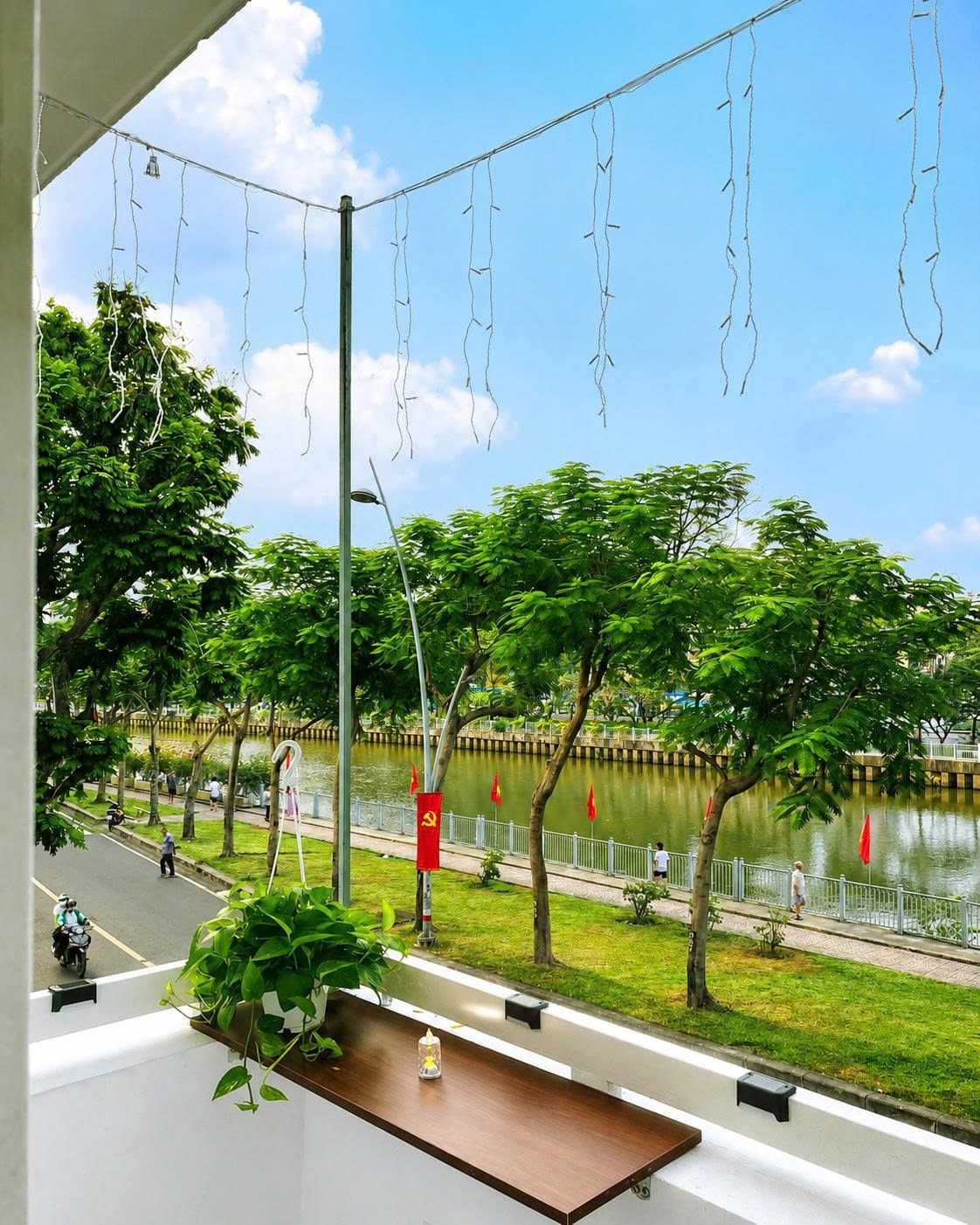 Una habitación con vista a un parque, un cuerpo de agua y una calle con vehículos.