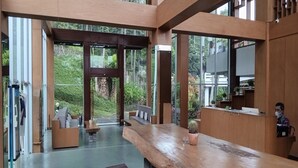 Un espace d’accueil avec un comptoir de réception en bois, des sièges et une vue sur la verdure environnante.