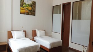 Une chambre d’hôtel avec deux lits simples, un plancher en bois et un tableau au mur.