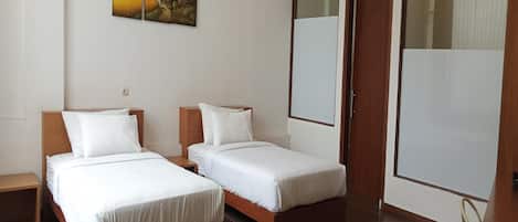 Habitación de hotel con dos camas individuales, suelo de madera y un cuadro en la pared.