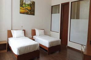 Ein Hotelzimmer mit zwei Einzelbetten, Holzboden und einem Bild an der Wand.