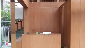 Un espacio interior de madera con un mostrador central, una escalera y una percha para ropa.