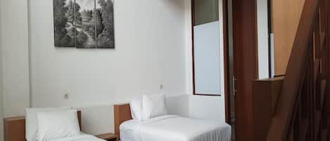 Habitación de hotel con dos camas individuales, un ventanal grande y un cuadro en la pared.