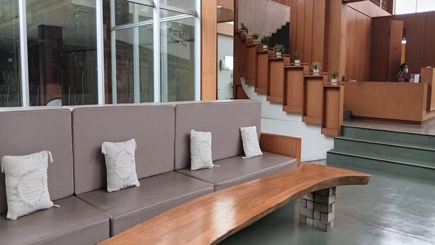 Zona de recepción con un largo banco de madera y asientos acolchados.