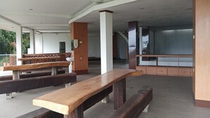 Un espacio de estar al aire libre con bancos de madera y piso de concreto.