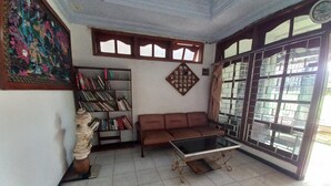 Ein Zimmer mit einer Couch, einem Couchtisch, einem Bücherregal und einer Dekofigur.