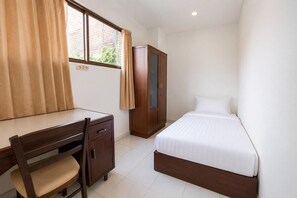 Ein Schlafzimmer mit einem Bett, einem Schreibtisch, einem Stuhl und einem Kleiderschrank.