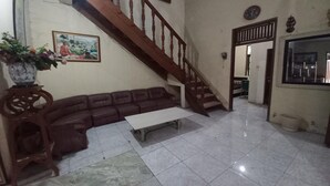 Una sala de estar con una escalera de madera, un sofá, una mesa de centro y una planta en maceta.