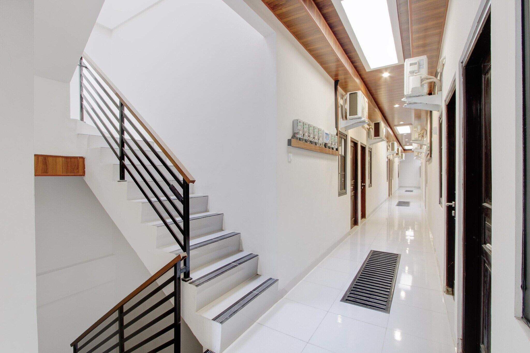 Un interior moderno con una escalera, un pasillo largo e iluminación empotrada en el techo.