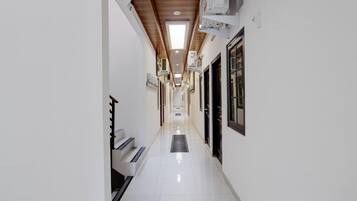 Un couloir propre et bien éclairé, avec un sol carrelé, qui mène à une porte au fond.