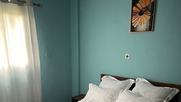 A bed with a quilted white bedspread, a wooden headboard, and white pillows. - Comfy Cityscape Elegance (Yaoundé)