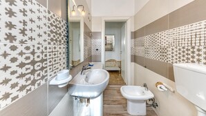 A modern bathroom with a large sink, a bidet, and a mirror.