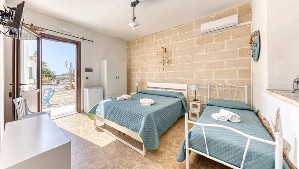 A bedroom with two beds, a desk, and a window overlooking a courtyard.