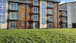 A multi-story residential building with balconies, large windows, and a flat roof. - SeaBeach View Coastal Path Ground Floor Apartment (LLANELLI)