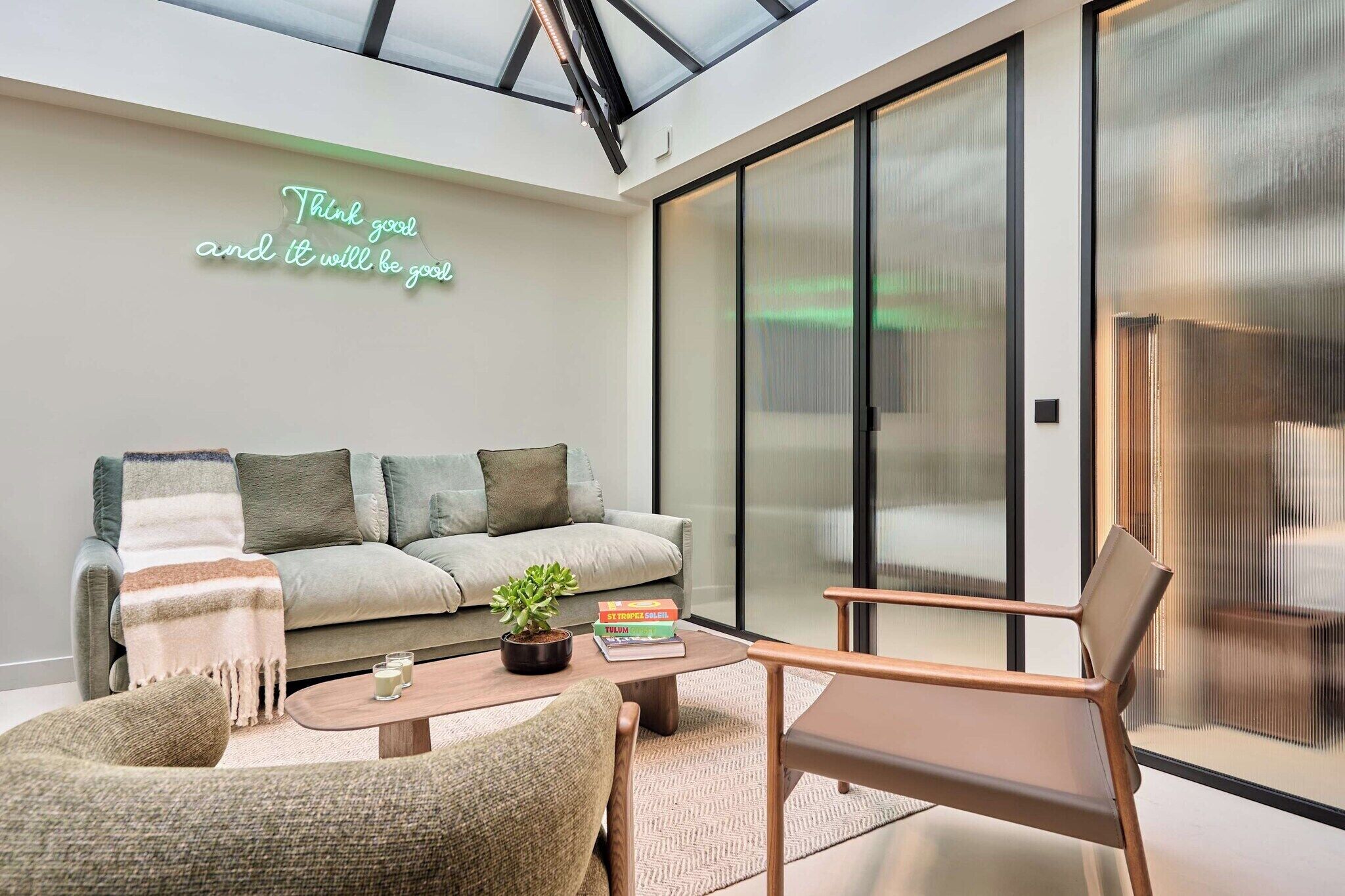 A modern living room with a sofa, armchairs, a coffee table, and a glass door leading to a balcony.