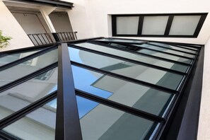 A modern building with a series of large, clear glass windows and a black frame. - Sublim Apartment - Le Marais - Beaubourg (Paris)