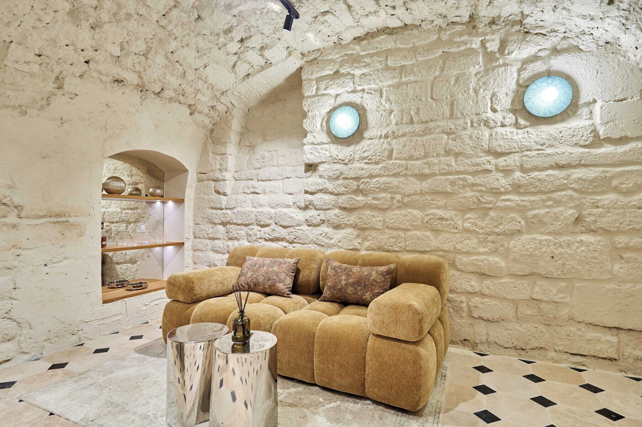 Ein gemütliches Zimmer mit Steinwand, einer Couch und einem kleinen Tisch mit Dekoration.