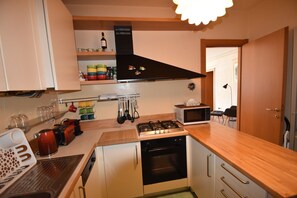 A compact kitchen with a stove, microwave, and various utensils. - Apartment in Verbania near Lake and Islands (Verbania)