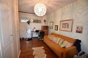 A living room with a sofa, a desk with a computer, a chair, and a decorative ceiling light. - Apartment in Verbania near Lake and Islands (Verbania)