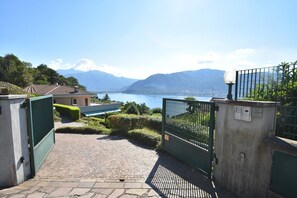A paved pathway leading to a gated entrance with a view of a lake and mountains in the background. - Apartment in Verbania near Lake and Islands (Verbania)