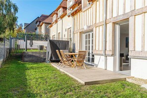 Ein Wohnhaus mit Terrasse, Sitzgelegenheit im Freien und einem überdachten Bereich.