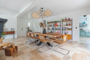 A spacious dining area with a long wooden table, six chairs, and a unique ceiling fan. - Exceptional House with Pool 12P – Englesqueville (Englesqueville-en-Auge)