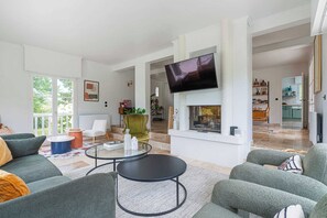 Una sala de estar moderna con chimenea, un televisor de pantalla plana y vistas a la cocina.