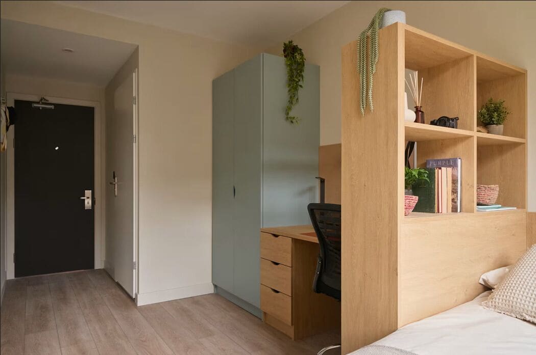Ein Schlafzimmer mit einem Bett, einem Schreibtisch mit Stuhl, einem Kleiderschrank und einem Bücherregal.