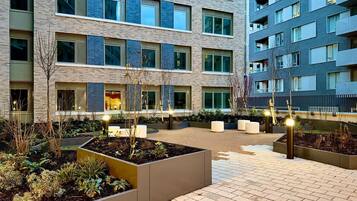 A multi-story residential building with a courtyard featuring planters and seating areas.