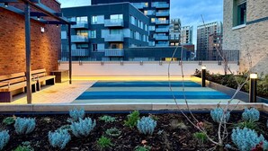 A modern building with multiple balconies, a rooftop pool, and a brick facade. - Student Only Ark Canning Town (London)