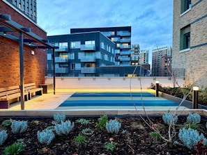Ein modernes Gebäude mit mehreren Balkonen, einem Dachpool und einer Ziegel-Fassade.