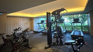 Een fitnessruimte met trainingsapparatuur, een loopband en een bank.