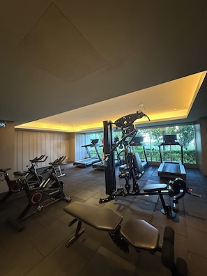 Ein Fitnessraum mit Trainingsgeräten, Laufband und Bank.
