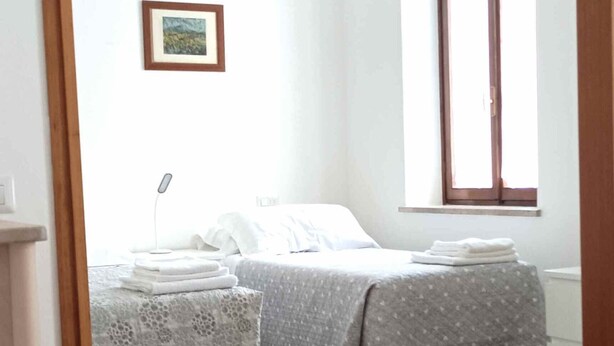 Quarto com duas camas, uma janela e um quadro na parede.