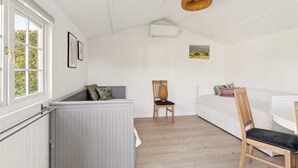 A room with a white radiator, a wooden chair, a white sofa, and a picture on the wall.