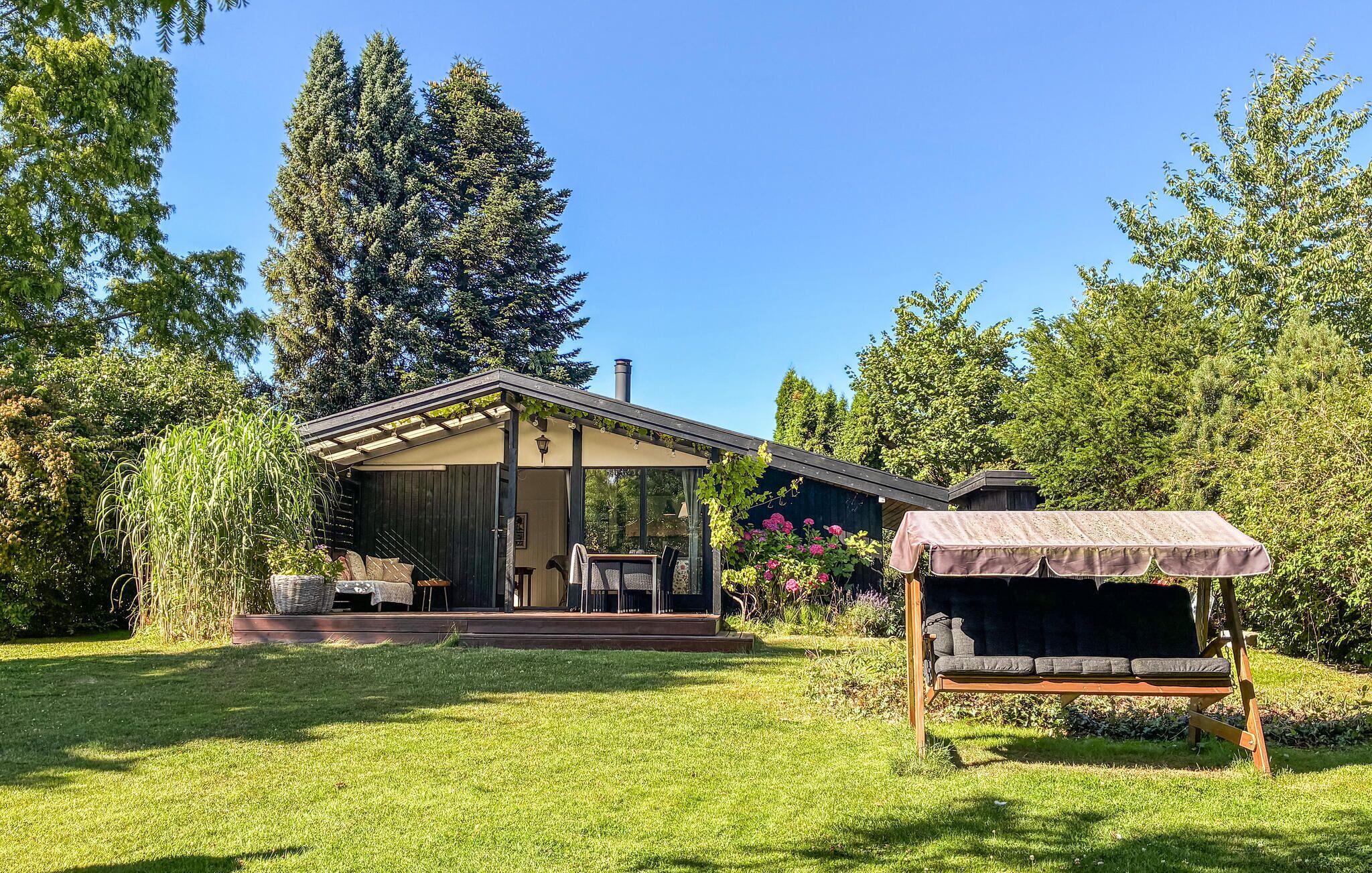 A modern house with a covered porch, a barbecue area, and a well-maintained lawn.